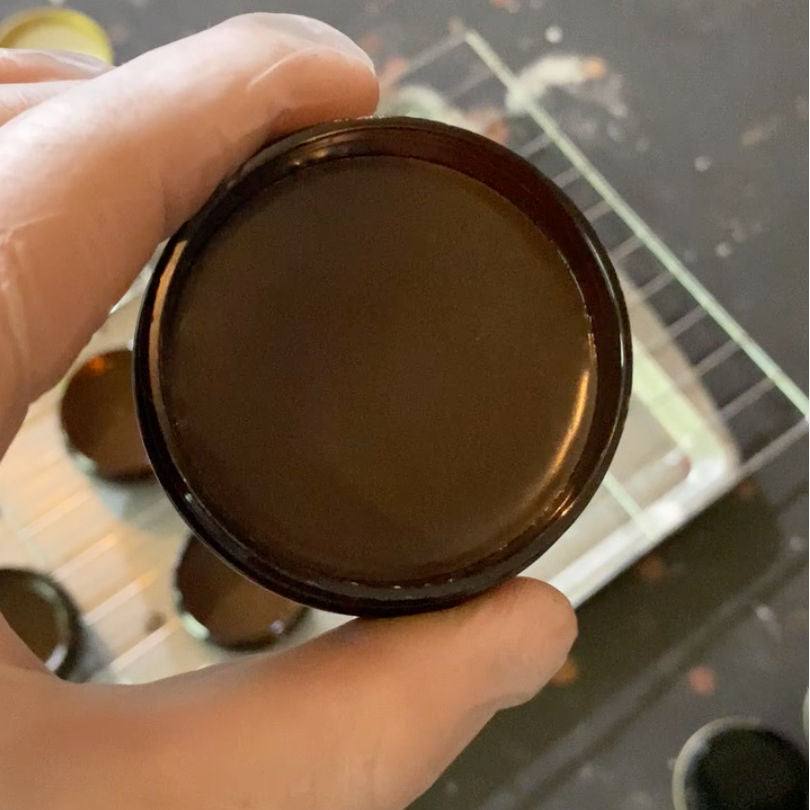 Brown Water Resistant Leather Cream used for preventing water spotting and rain penetration of brown leather shoes and boots - held in a gloved hand