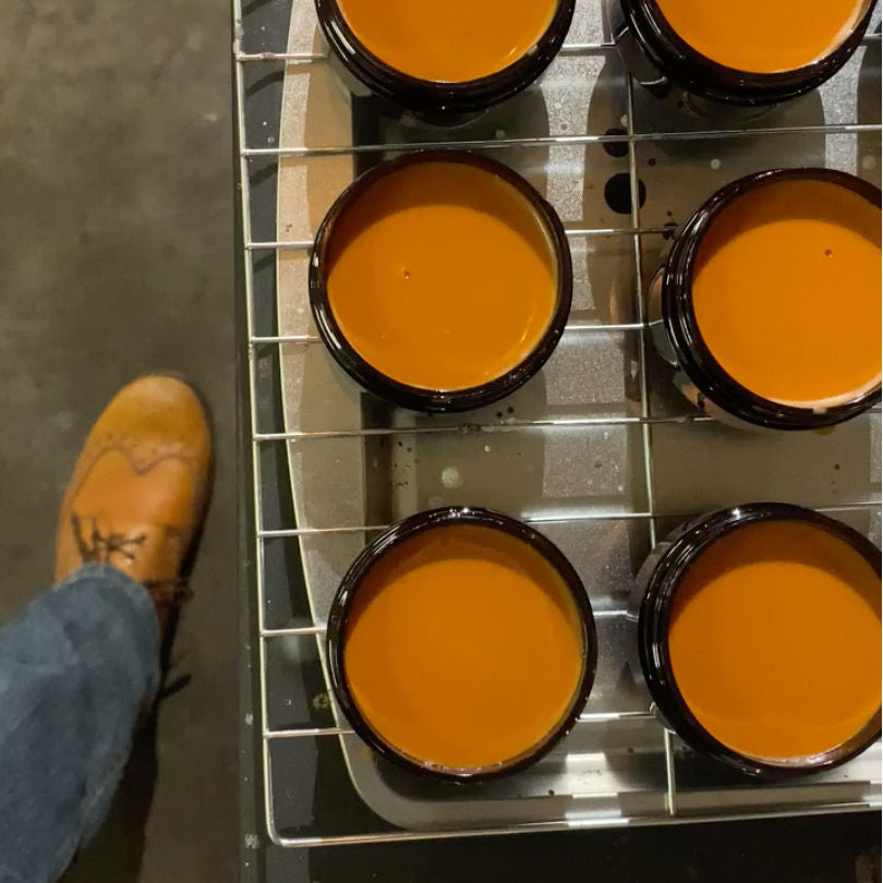 Fresh batch poured of Light Brown Leather Cream Polish still on the rack next to a pair of light brown boots